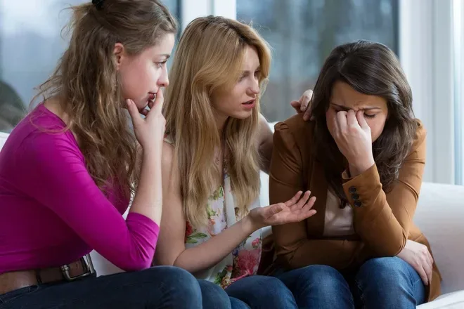 Ba người phụ nữ trò chuyện, một người buồn bã được bạn bè an ủi